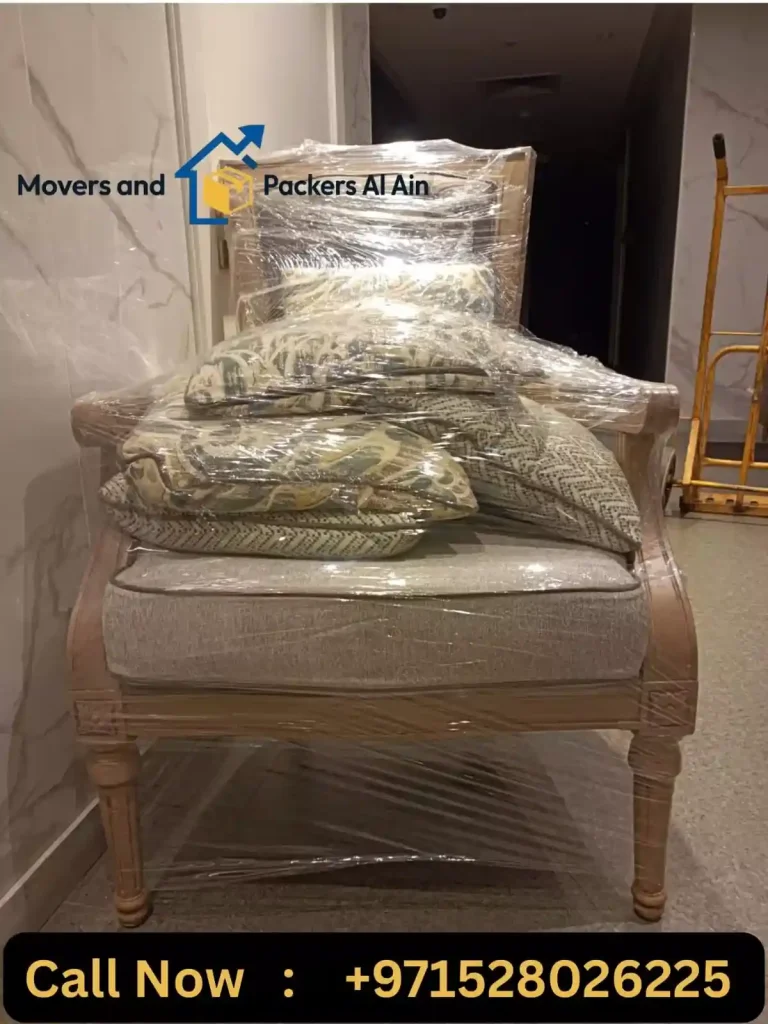Professional movers wrapping a sofa with protective material before relocation.